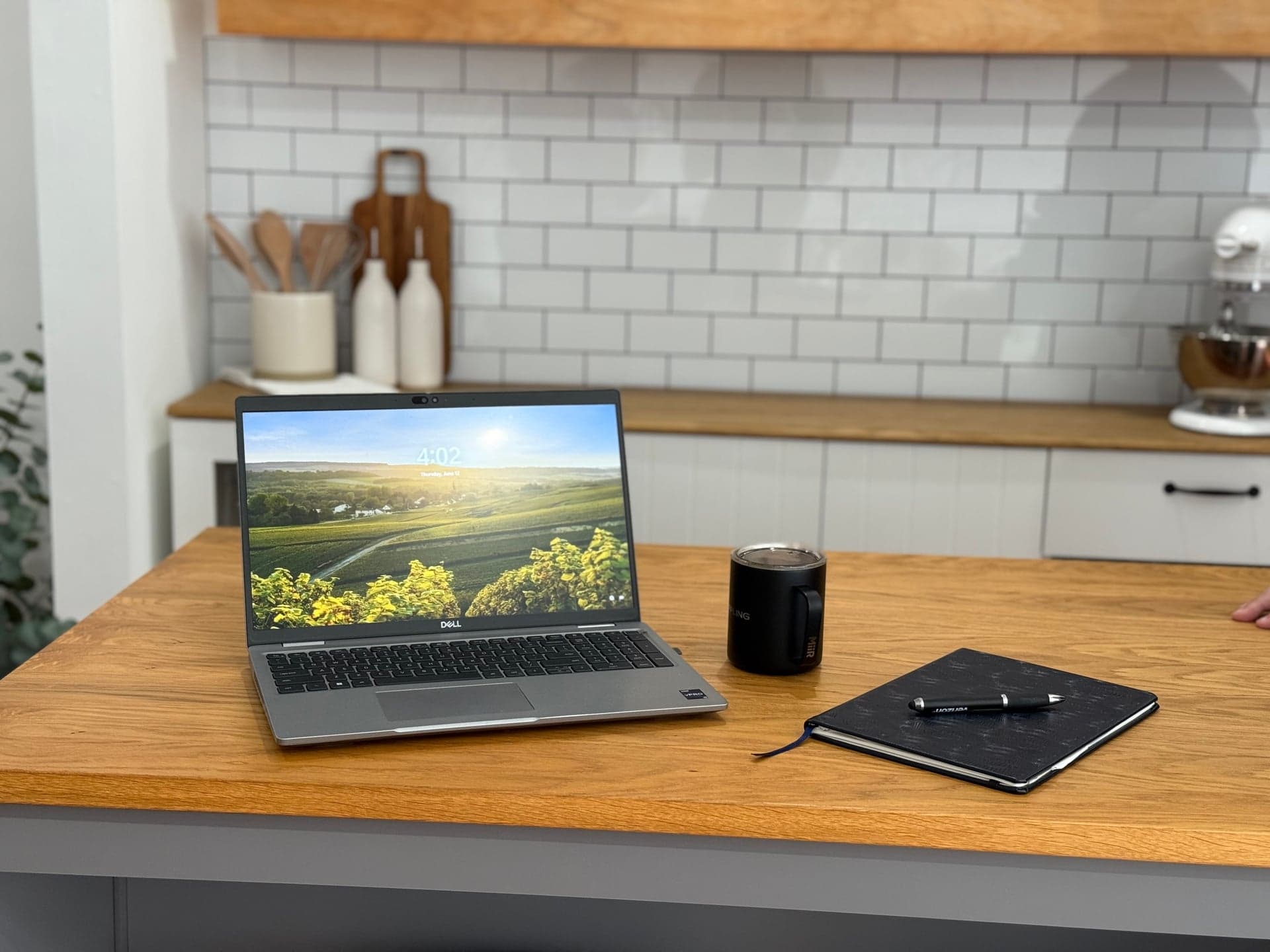 Laptop, coffee mug, and Valor notebook on a wooden kitchen island