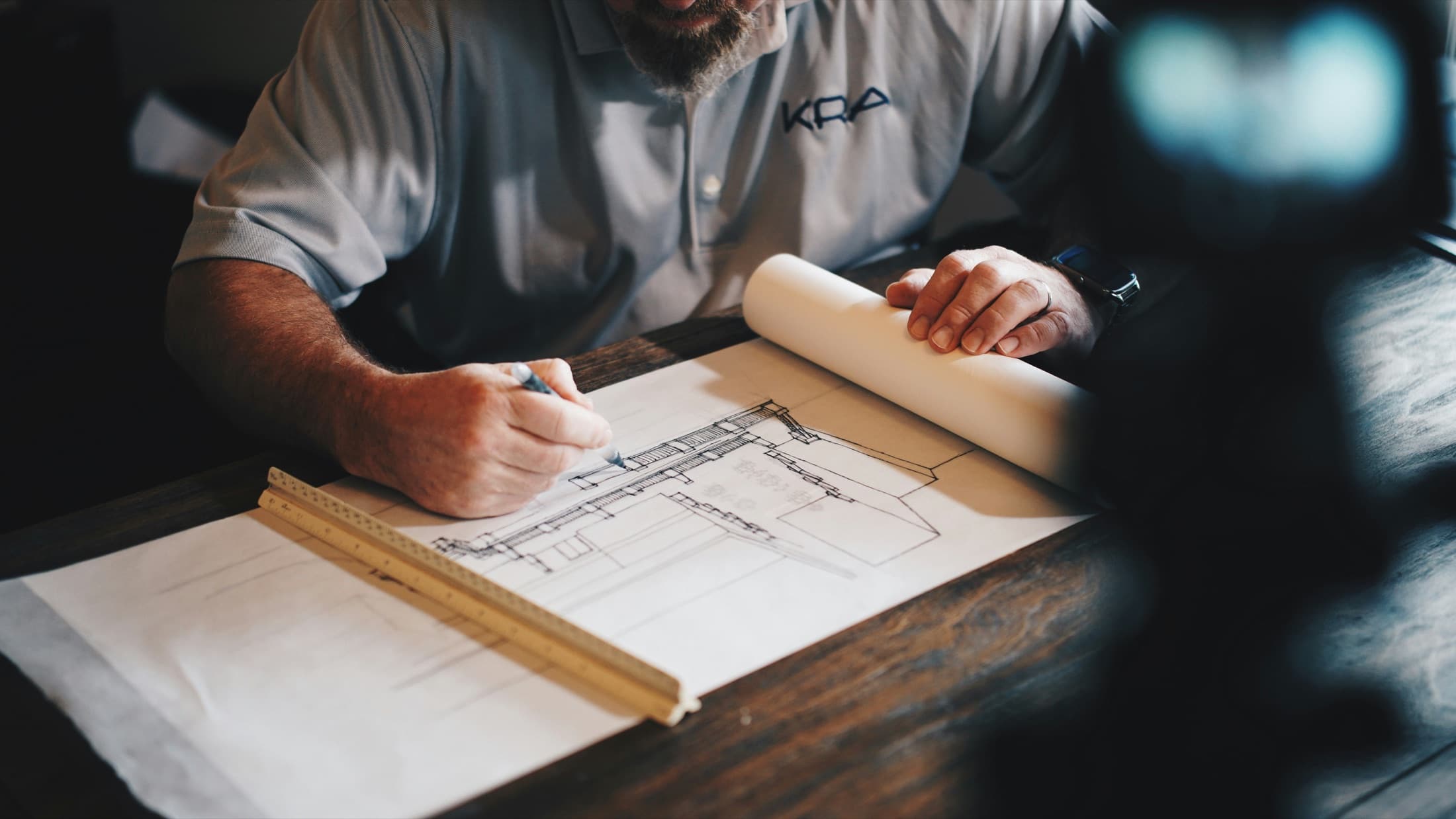 Contractor drawing plans at a desk for a construction project