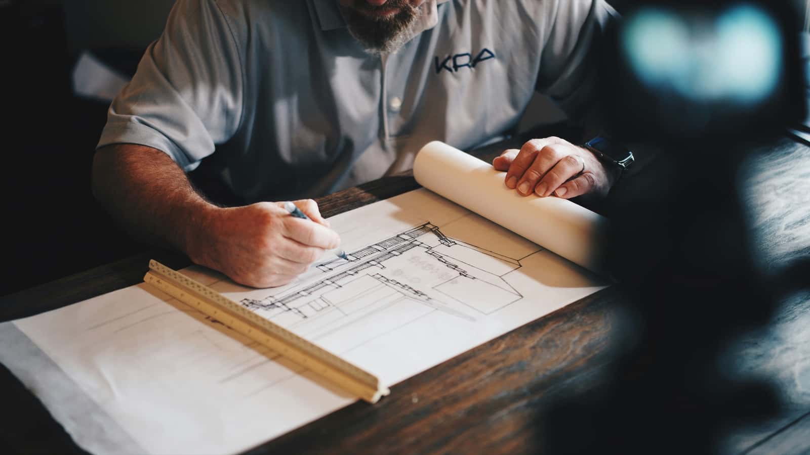 Contractor drawing plans at a desk for a construction project